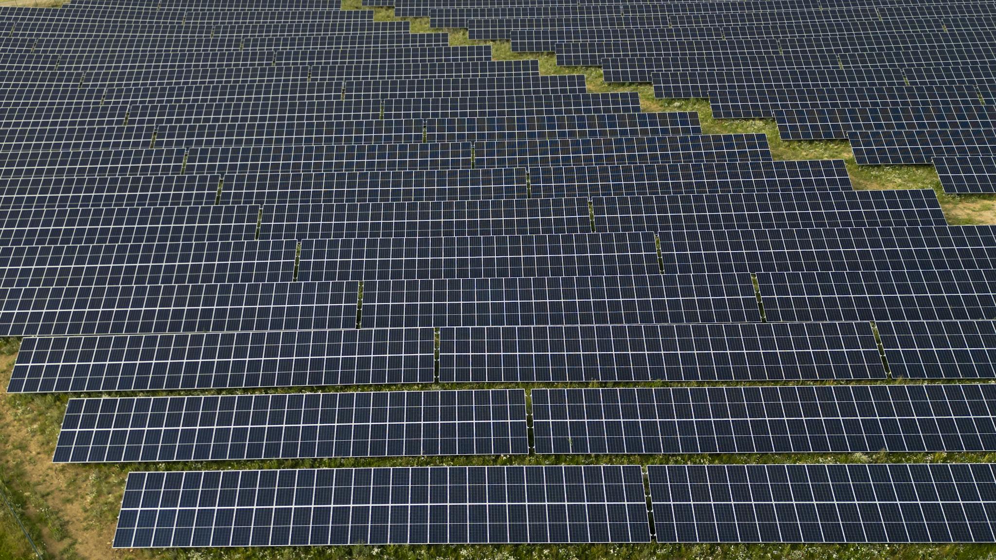 Aerial photograph capturing the geometric layout of a large solar panel farm. Sustainable energy focus.